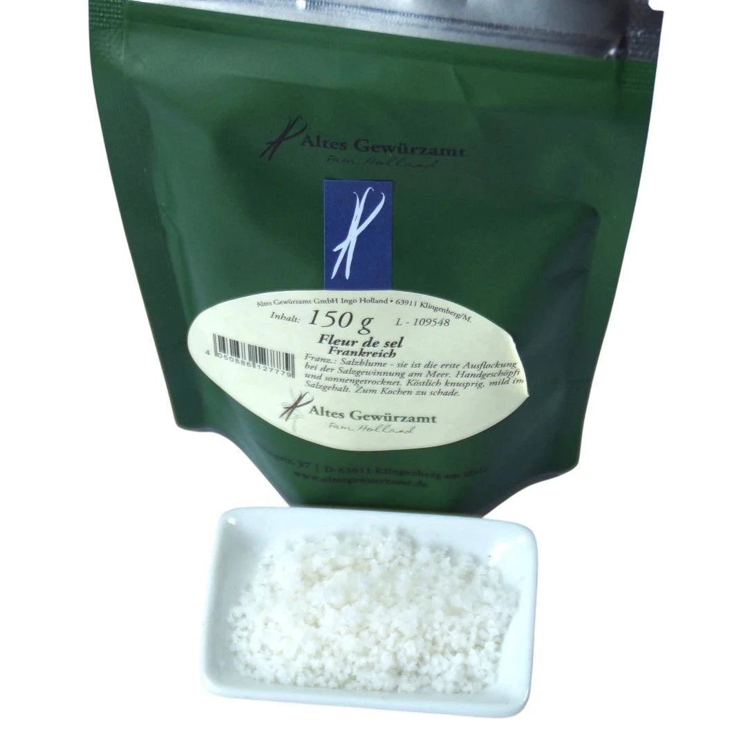 Altes Gewürzamt Fleur de Sel Handgeschöpfte französische Salzblume, grüner Gewürzbeutel und ein kleines Schälchen mit Salzflocken auf hellem Hintergrund