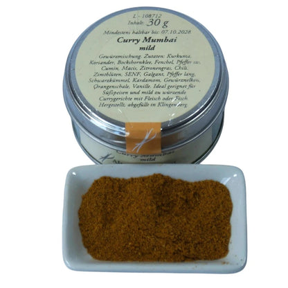 Altes Gewürzamt Curry Mumbai Mild-fruchtige Premium-Currymischung, grüne Gewürzdose von oben und ein kleines Schälchen mit Currypulver auf hellem Hintergrund