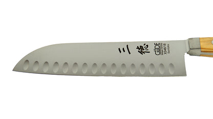 GÜDE Klinge des Santoku Alpha Olive X546/18 – Japanisches Kochmesser mit Kullenschliff 18 cm Klingenlänge mit Olivenholz-Griff auf weißem Hintergrund