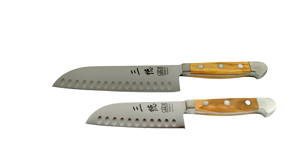 GÜDE Santoku Alpha Olive X546/14 und X546/18 – Japanisches Kochmesser mit Kullenschliff 14 cm und 18 cm Klingenlänge mit Olivenholz-Griff auf weißem Hintergrund im Vergleich